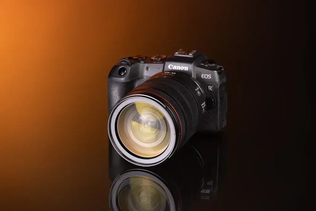 Fotocamera mirrorless Canon nera con obiettivo zoom montato, su fondo arancione