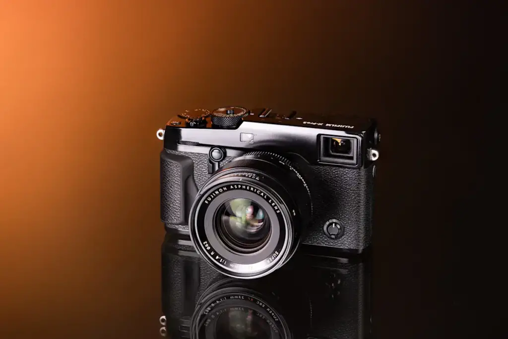 Fotocamera mirrorless Fujifilm X-Pro2 in stile telemetro con obiettivo XF 23mm su fondo arancione