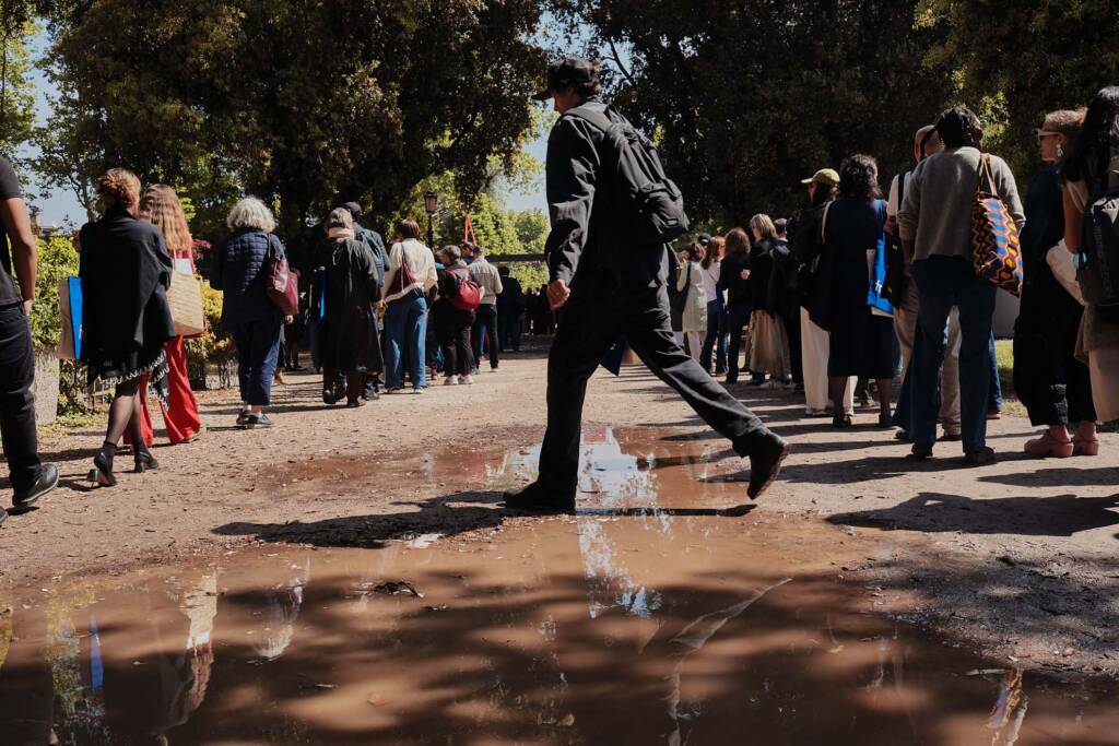 Fila di visitatori lungo un muro davanti a una scultura ai Giardini di Venezia