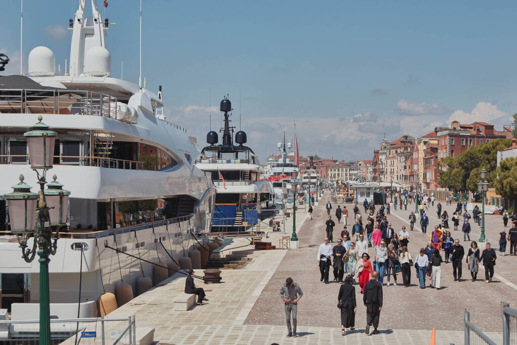 Mega yacht bianco ormeggiato lungo la riva mentre le persone camminano sul fronte d’acqua