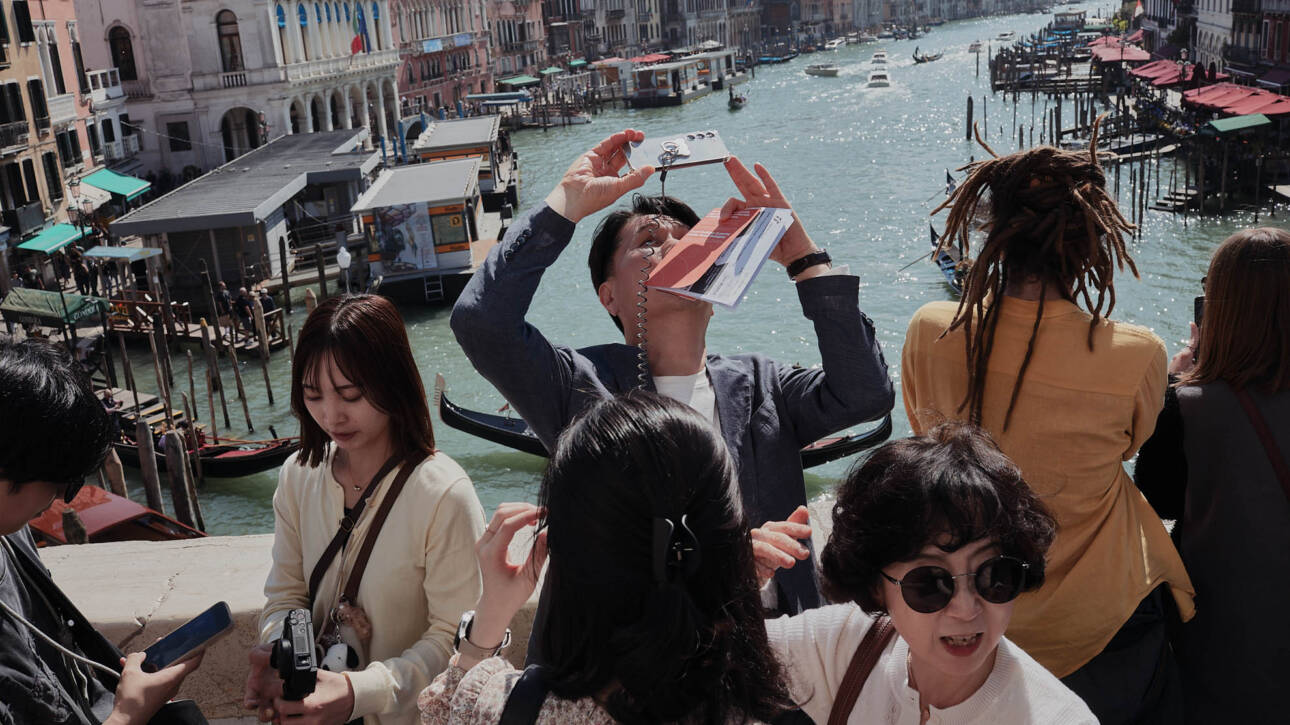 Gruppo di turisti fotografa il Canal Grande con gli smartphone alzati dal ponte di Rialto
