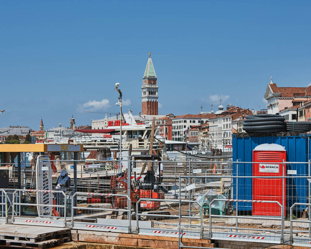 Impalcature e container di cantiere in primo piano con il campanile di San Marco sullo sfondo