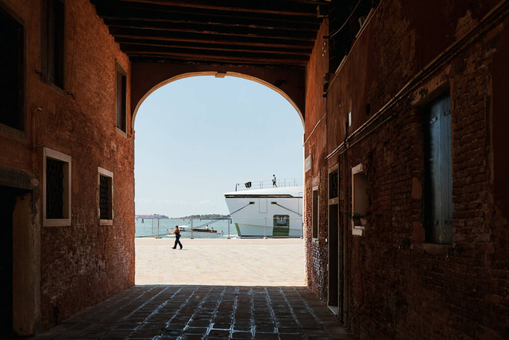 Grande nave bianca inquadrata attraverso l’arco scuro di un sottoportego veneziano
